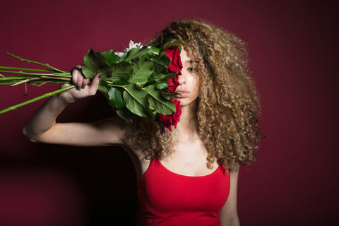 CharmaineLouise Books CLBooks Sexy pretty Dominatrix woman with long curly brown blonde hair wearing red fitted tank top holding red roses